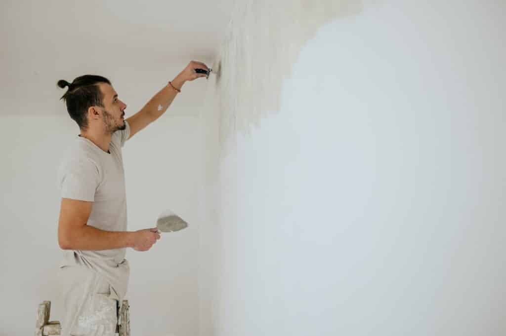 A plasterer is using building tools for plasterwork and skim coating.