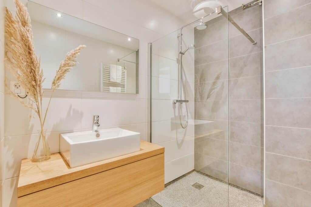 Fabre Occitanie - Une salle de bain moderne avec cabine de douche vitrée, lavabo, et le savoir-faire d'un carreleur tarn-et-garonnais pour un carrelage impeccable.