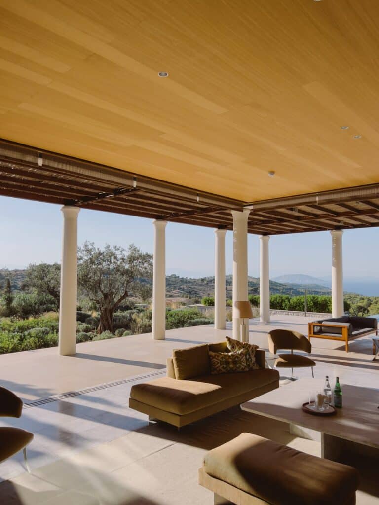 Lounge area with soft sofas and armchairs on an open terrace with columns. Hotel Amanzoe, Greece