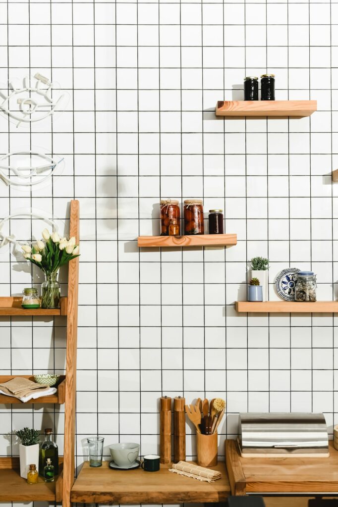 Fabre Occitanie - Un coin cuisine moderne à Fabre Occitanie avec des étagères flottantes en bois sur un mur carrelé blanc, rangeant bocaux et accessoires de cuisine.