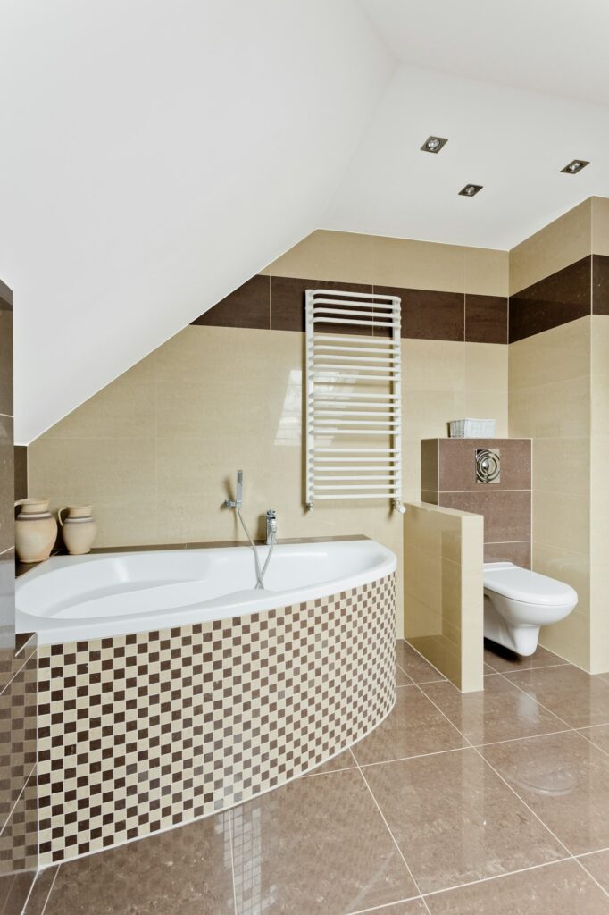 Fabre Occitanie - Salle de bain moderne avec baignoire d'angle, carrelage beige et coin toilette séparé.