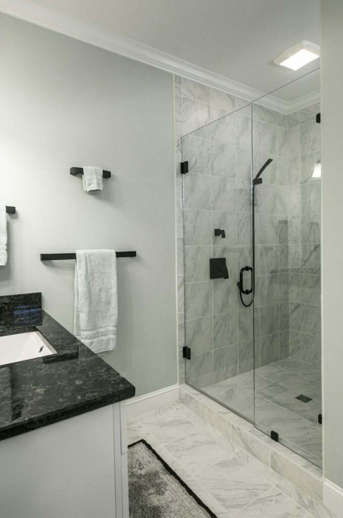 Fabre Occitanie - Salle de bains moderne avec carrelage en marbre et cabine de douche à porte vitrée.