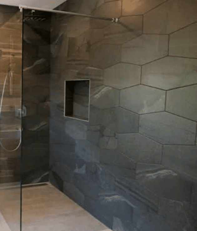 Fabre Occitanie - Salle de bains moderne avec carrelage texturé gris et cloison de douche en verre.