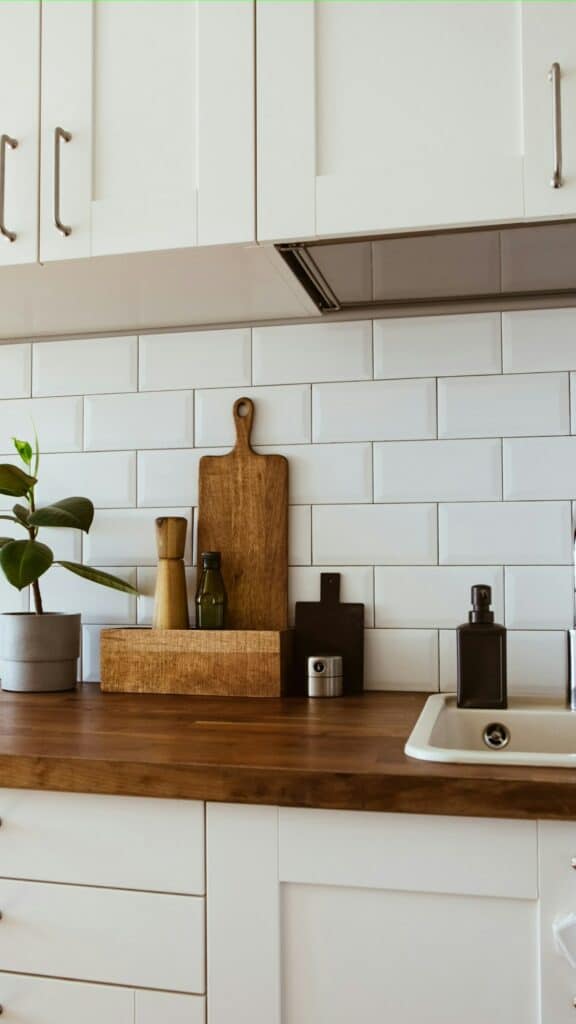 Fabre Occitanie - Comptoir de cuisine moderne avec carrelage métro blanc, planche à découper en bois, ustensiles et plantes en Fabre Occitanie.