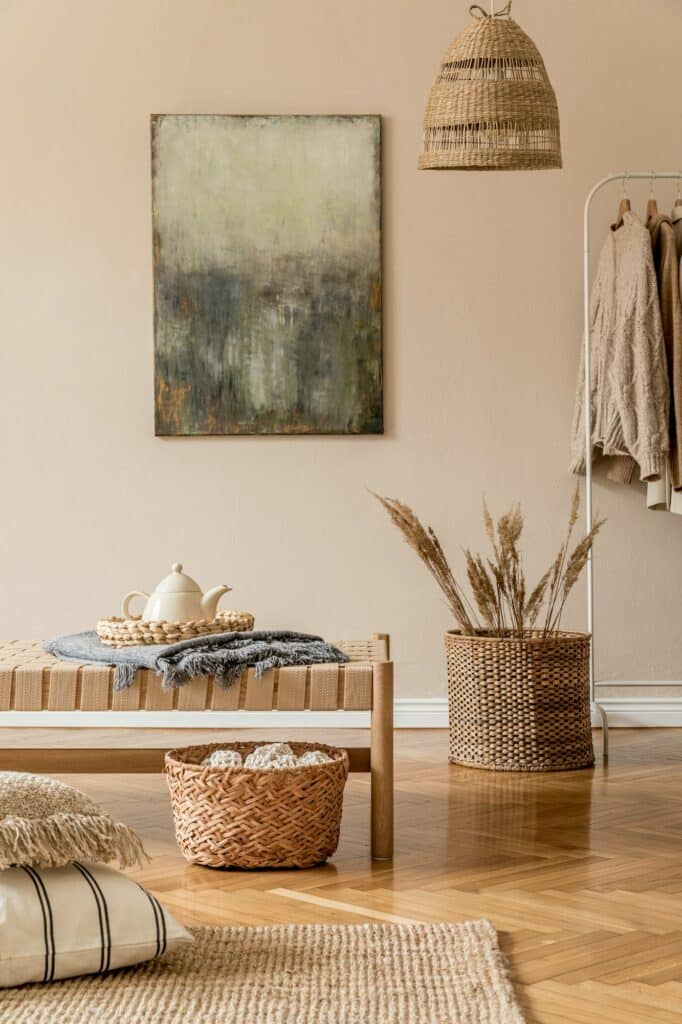 Fabre Occitanie - Une pièce cosy avec un tableau abstrait au mur, une suspension tressée, un banc avec coussins et un panier de plantes séchées de Fabre Occitanie.