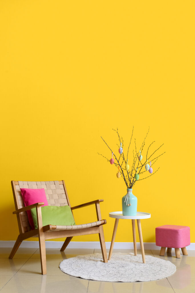 Fabre Occitanie - Un aménagement intérieur élégant avec un fauteuil en bois, un tapis rond et une petite table avec un vase décoratif contre un mur jaune à Fabre Occitanie.